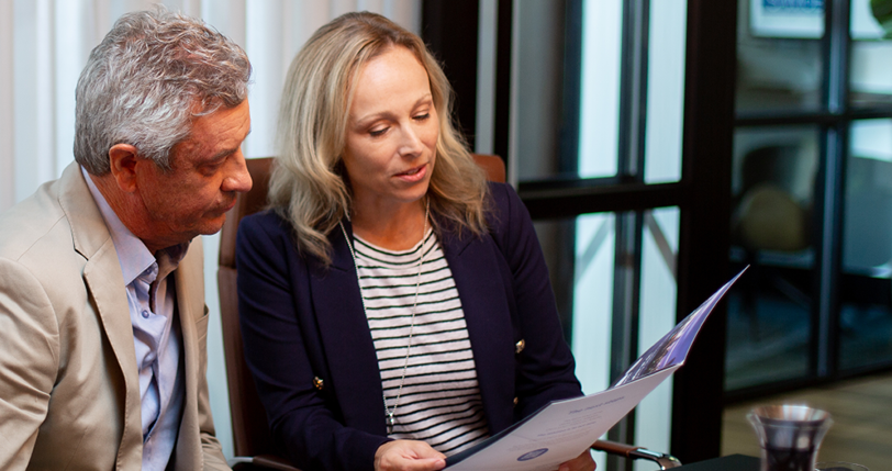 A middle age couple looking at a First Samuel Brochure about our ethical overlay