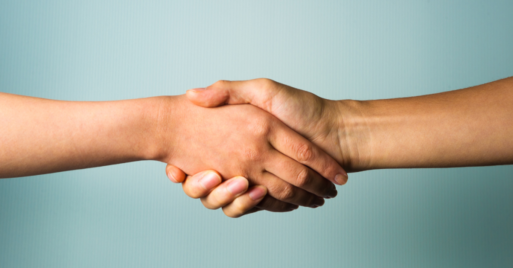 Two people shaking hands with a light blue background
